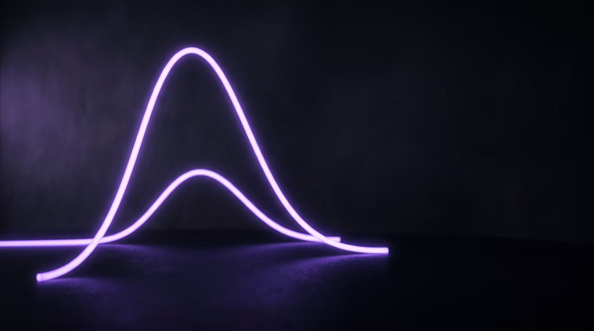 Editorial dark studio image of two glowing violet wave-form curves across a black surface, one peaking far higher, representing seasonal search demand